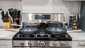A kitchen with a stainless steel stove, four pots with lids, a spice rack, and a knife block. - New Spacious 3 Bedroom Apt in the Heart of Philly (Philadelphia)