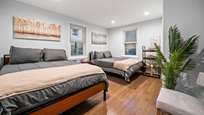 A modern bedroom with two beds, a desk, and a large window. - New Spacious 3 Bedroom Apt in the Heart of Philly (Philadelphia)