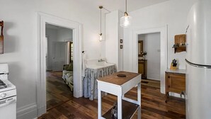 Pieni, käytännöllinen keittiö, jossa on puinen pöytä, jääkaappi ja pesuallas.