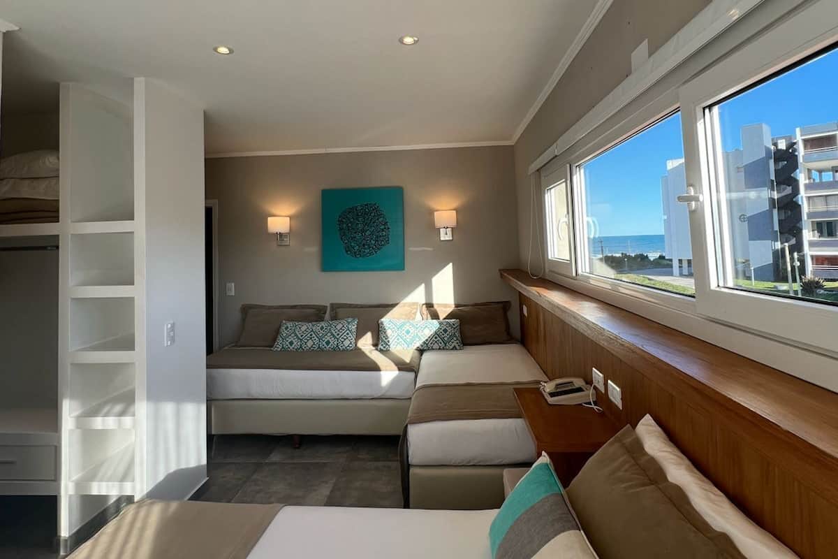 Una habitación de hotel con cama, zona de estar con vistas y ventana.