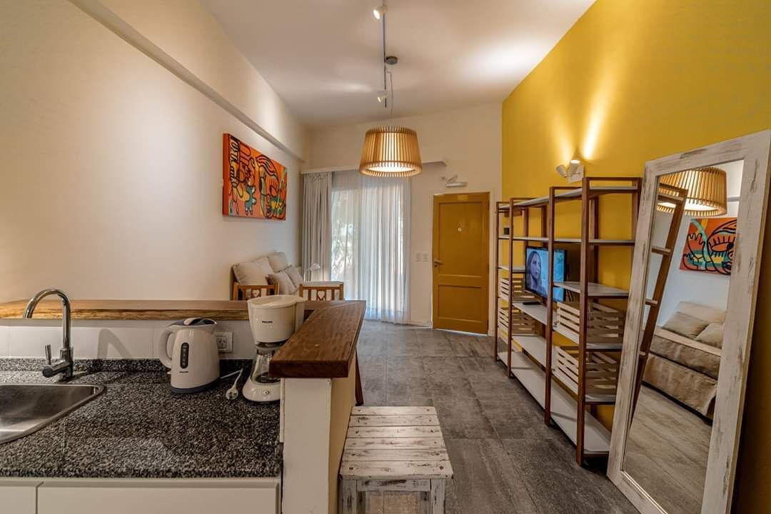 Una habitación de hotel compacta con kitchenette, comedor, zona de estar y televisor.