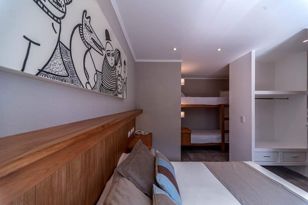 A modern bedroom with a wooden headboard, a bunk bed, and a large wall art piece.