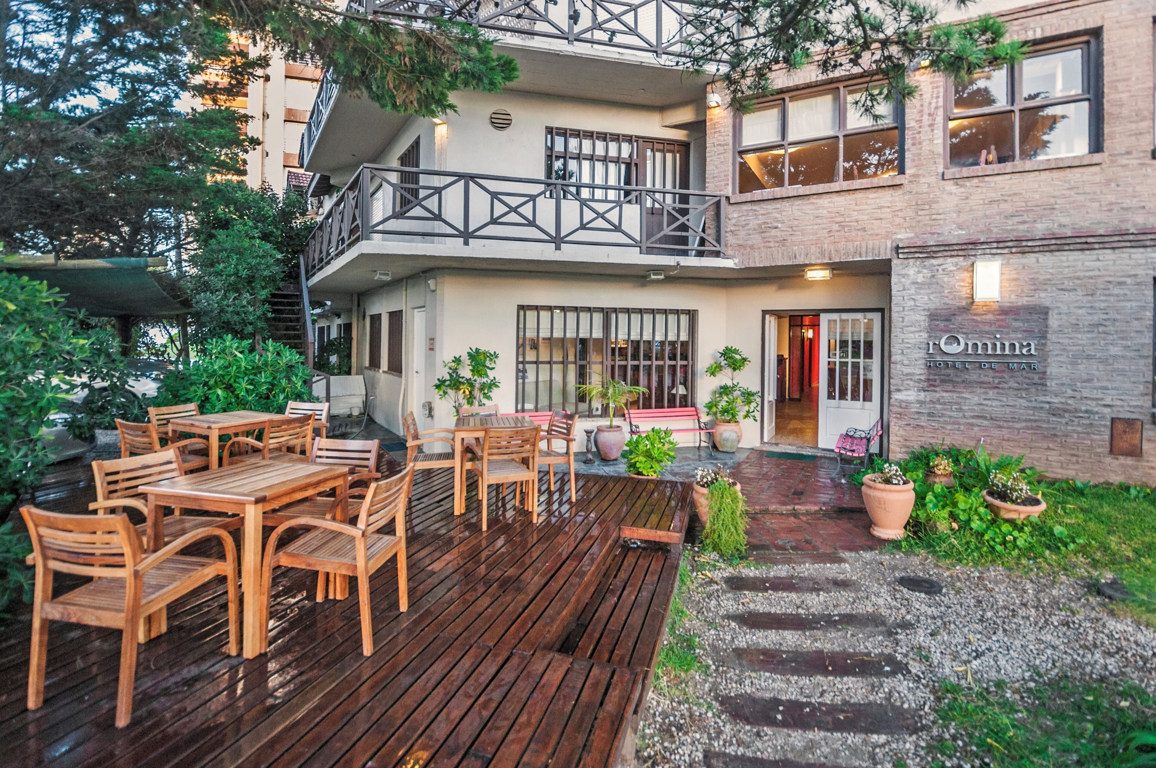 Un hôtel doté d’une terrasse en bois, d’un espace salon extérieur et de plantes en pot.