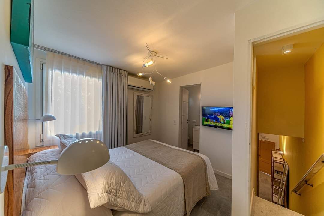 A hotel room with a bed, a ceiling fan, a TV, and a window with curtains.