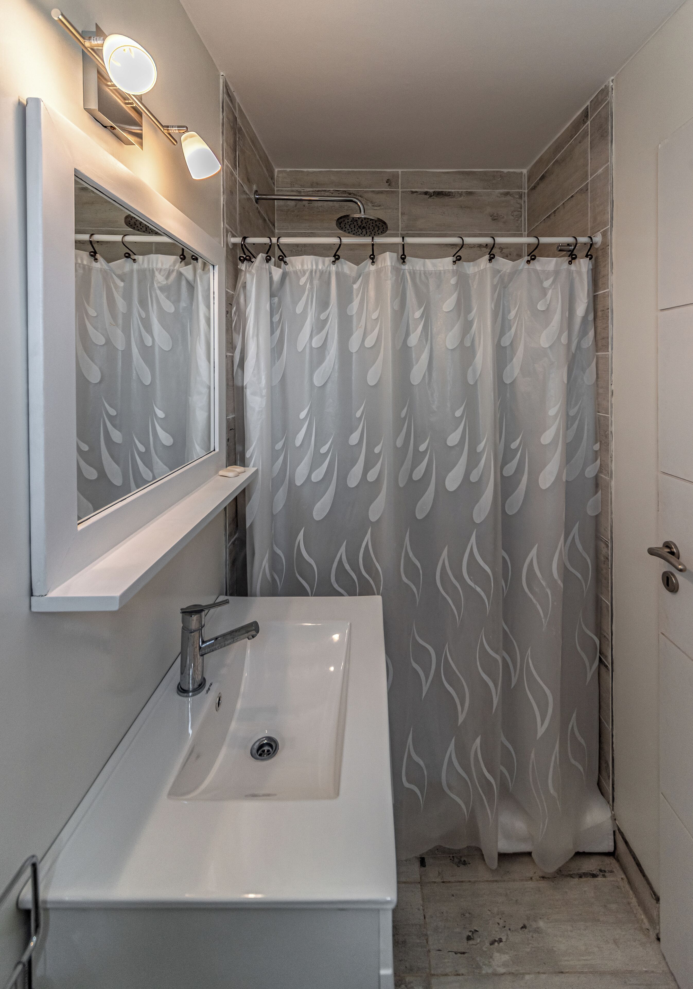 A bathroom with a white sink, a mirror, and a shower curtain with a flame pattern.