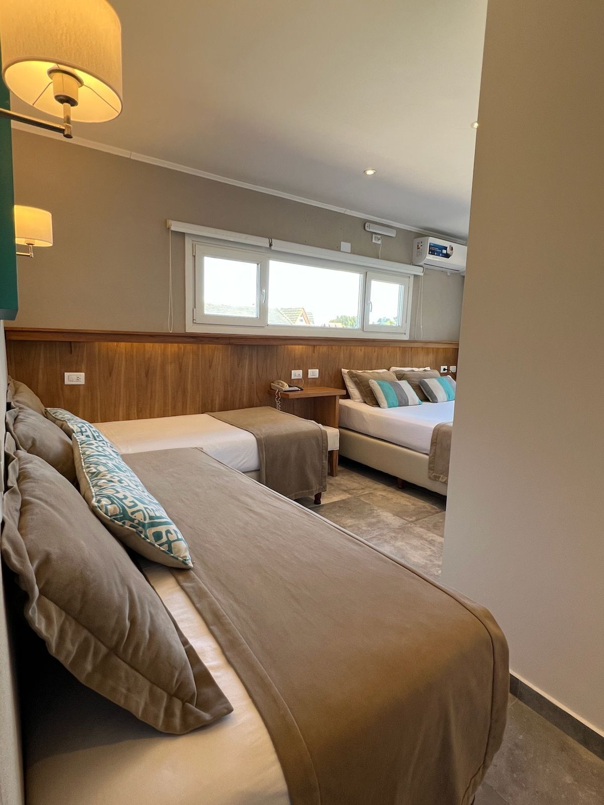 A room with two beds, a small table, and a window.