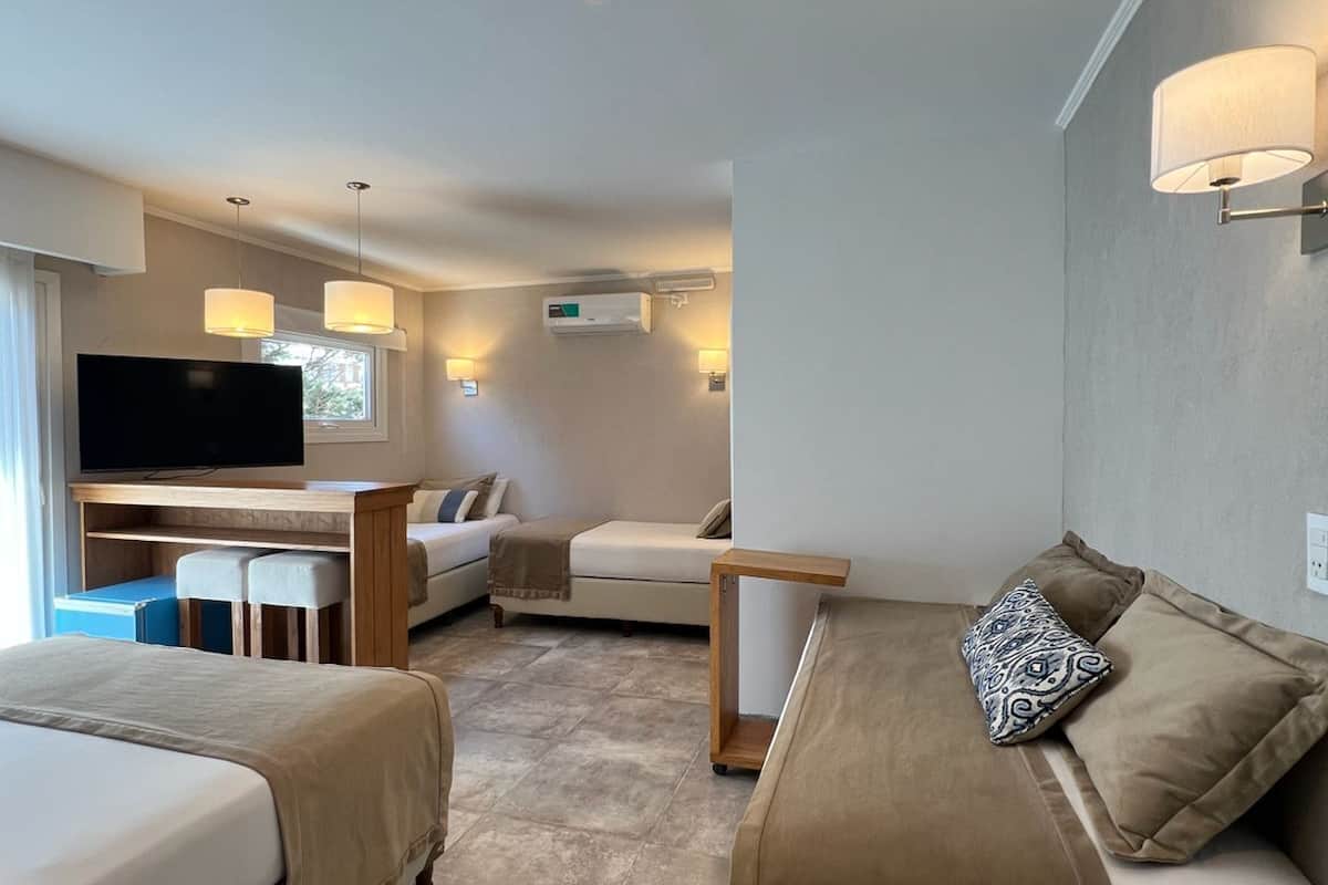 Habitación de hotel con dos camas, un escritorio, una televisión y un sofá.