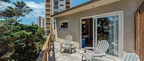 A balcony with outdoor seating and a view of a tall building.