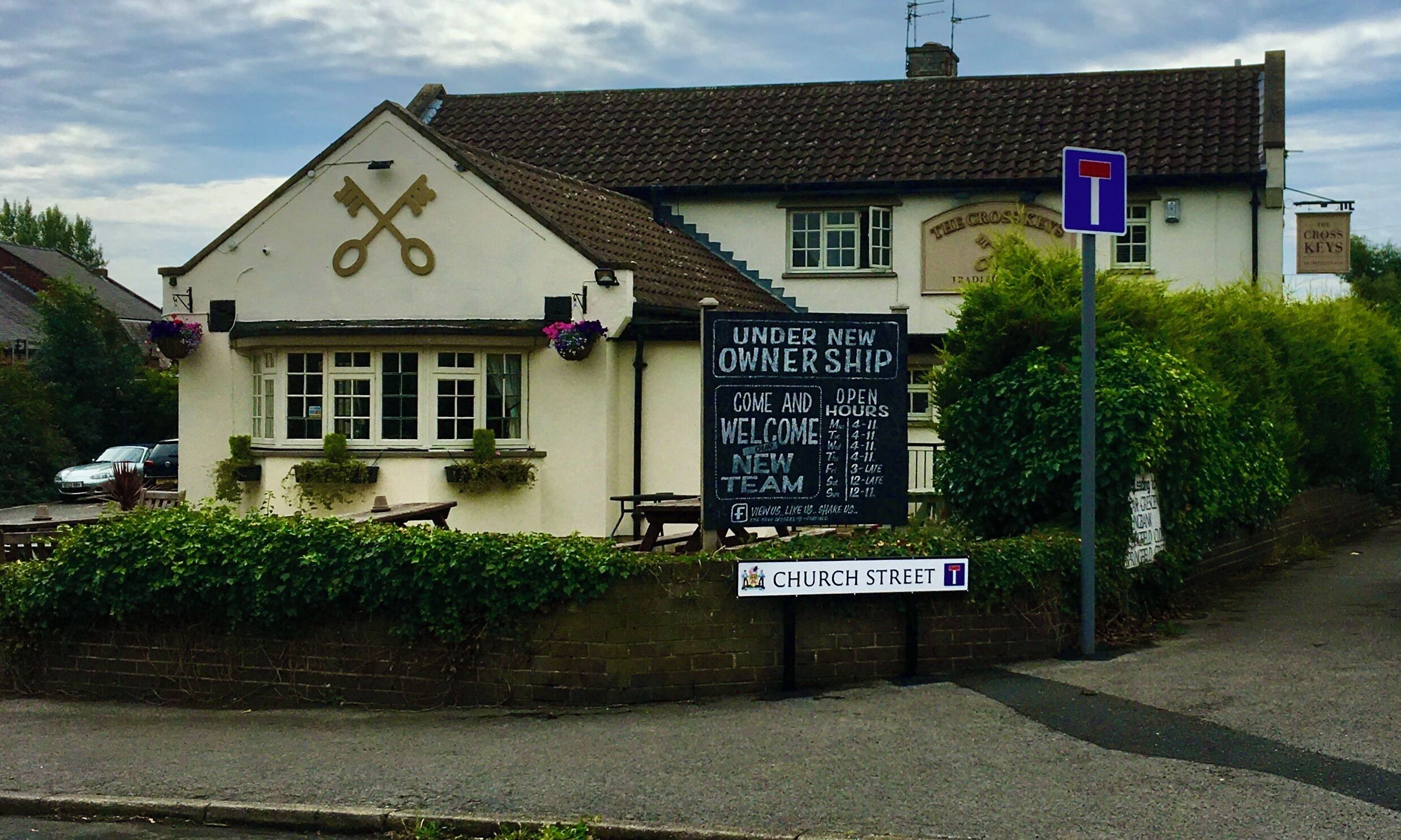 A pub with a sign indicating a new owner and open hours.