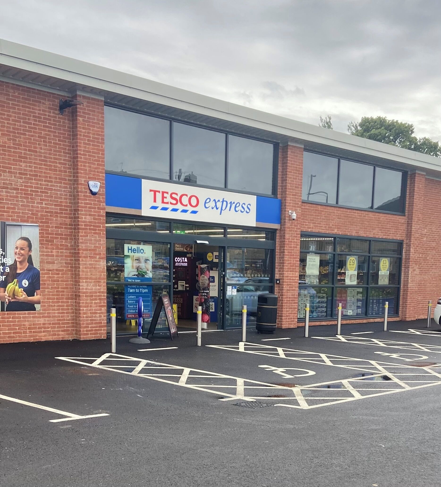 En Tesco Express butik med tydelig indgang, synlig skiltning og en parkeringsplads med afmærkede pladser.