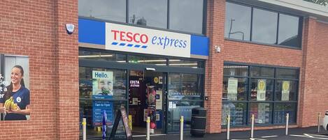 En Tesco Express butik med tydelig indgang, synlig skiltning og en parkeringsplads med afmærkede pladser.
