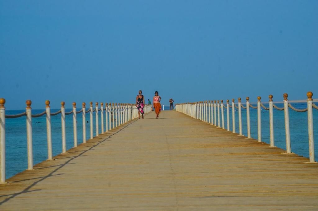 A long pier with white balustrades and a clear blue sky.