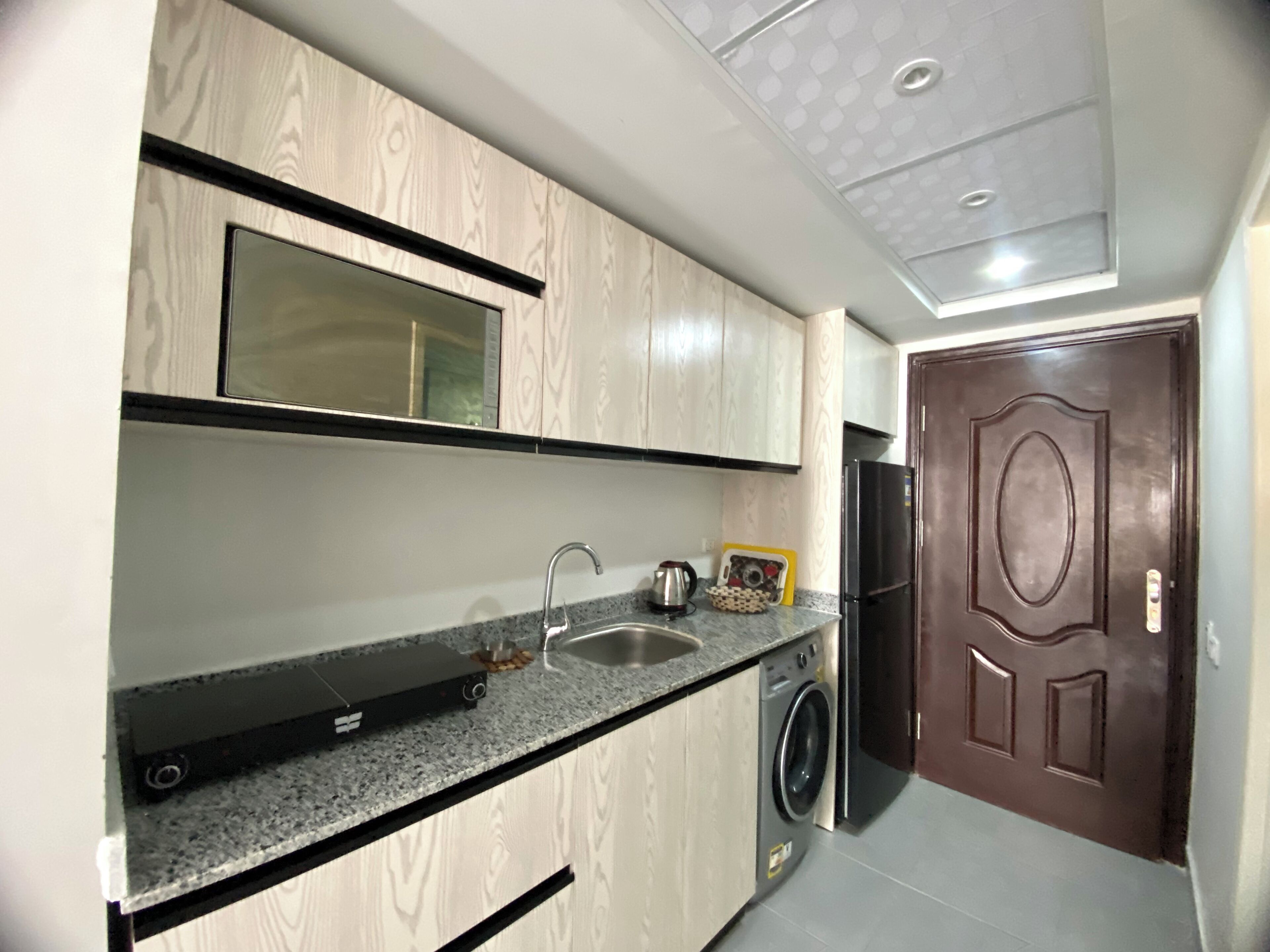 A compact kitchen with a built-in washing machine, a sink, and a microwave.