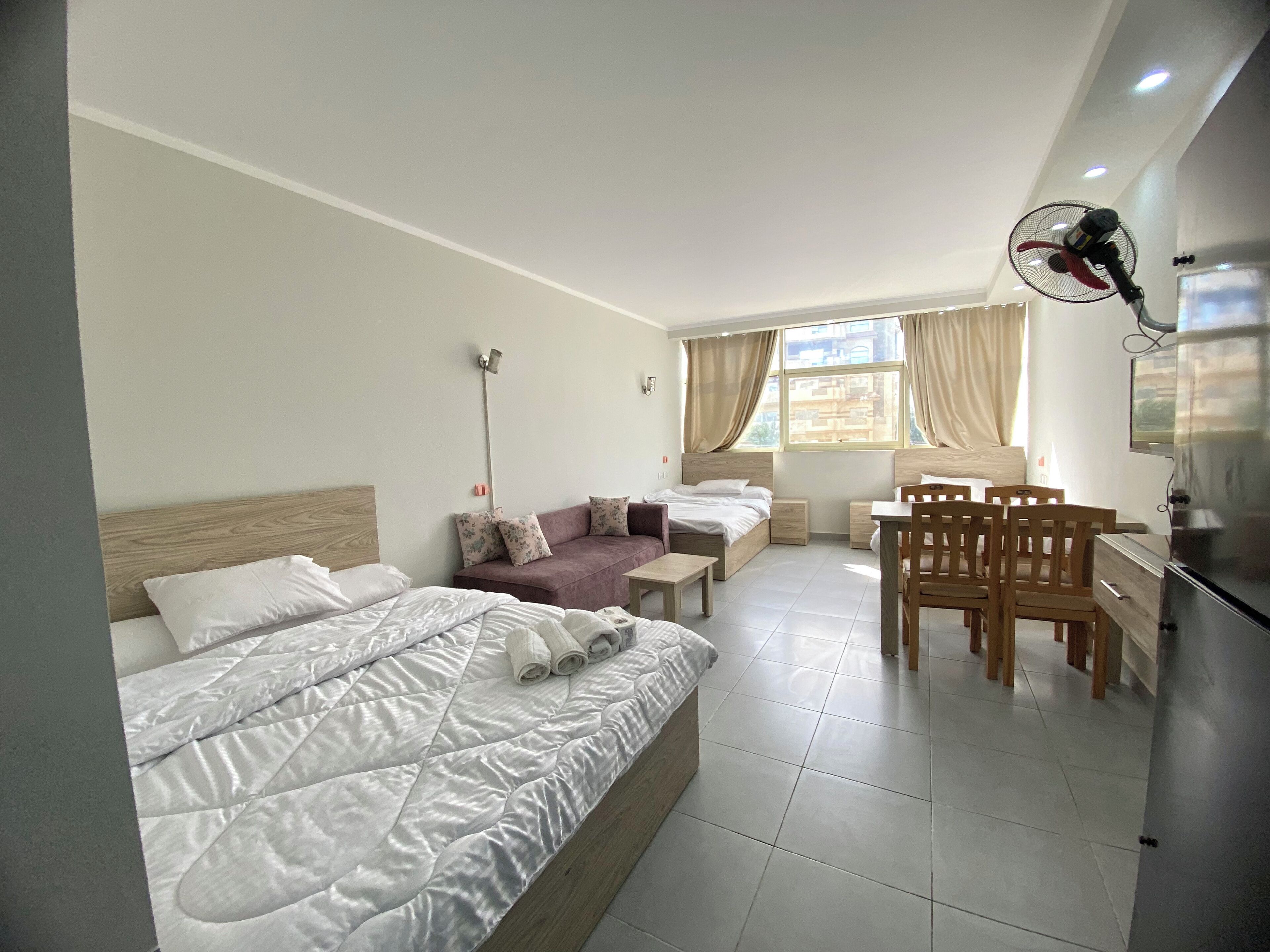 A hotel room with a bed, a sofa, a desk, and a chair.