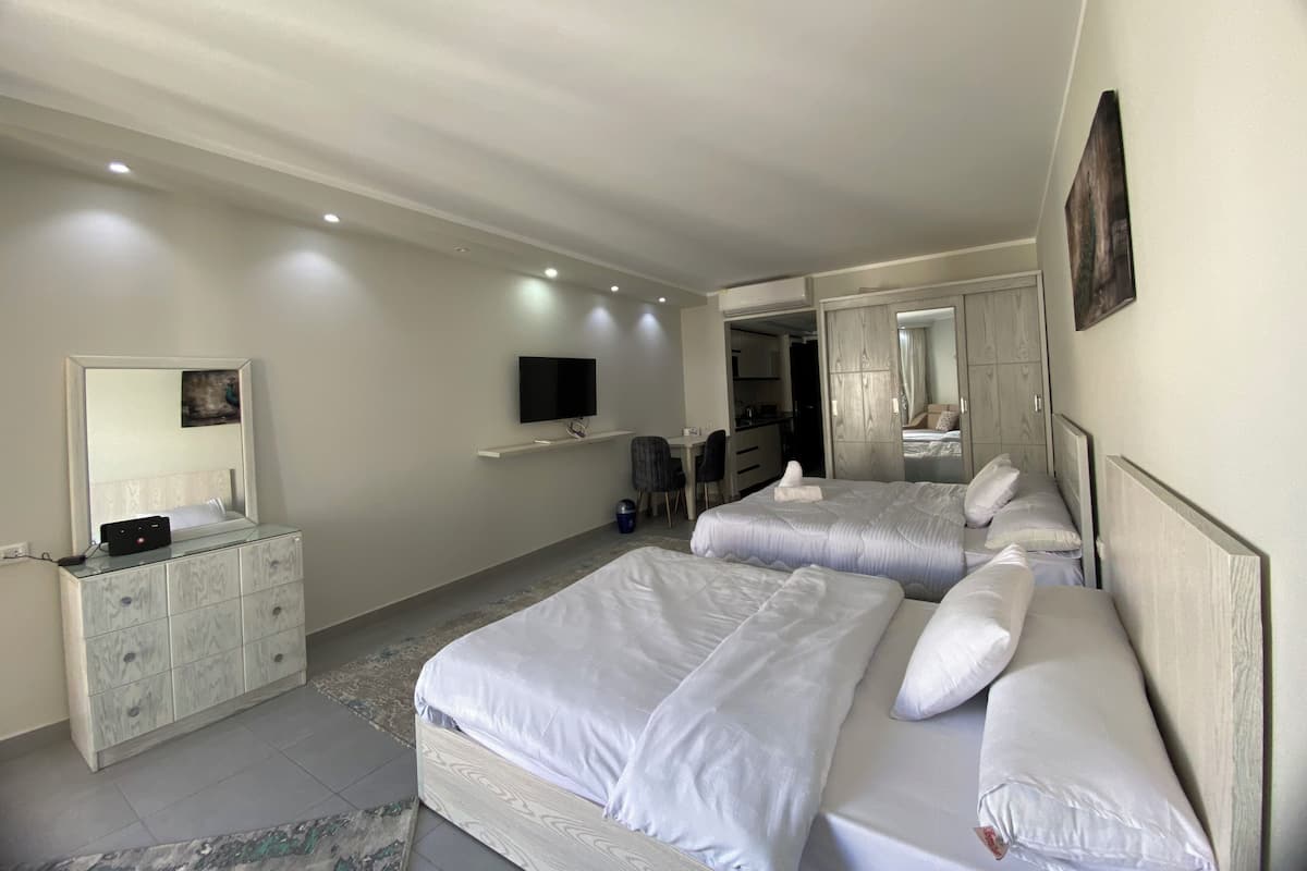 A modern hotel room with two beds, a TV, a dresser, and a mirror.