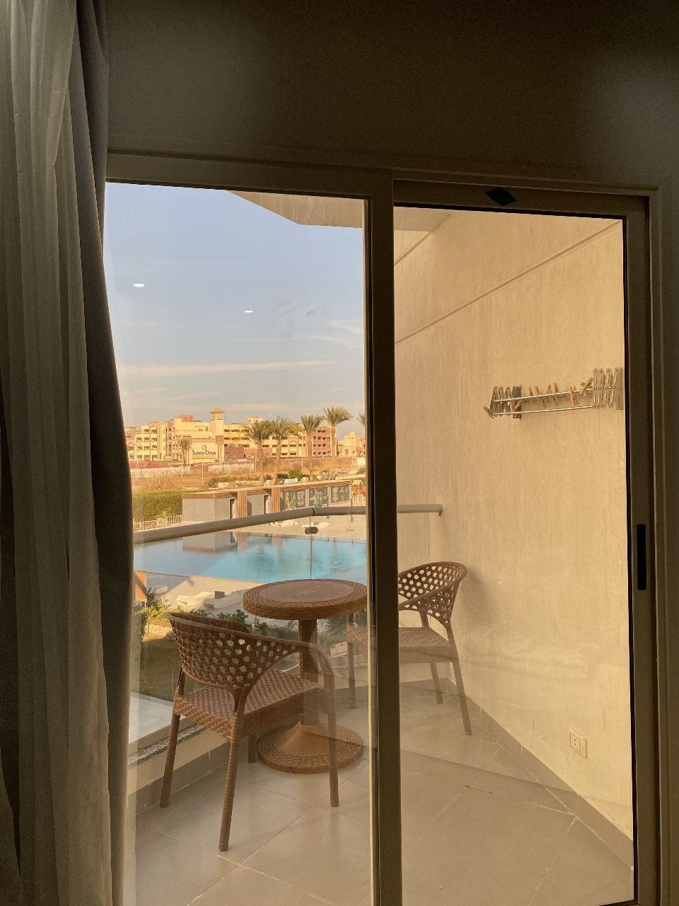 Ein Balkon mit Pool, Korbstühlen und einem Tisch.