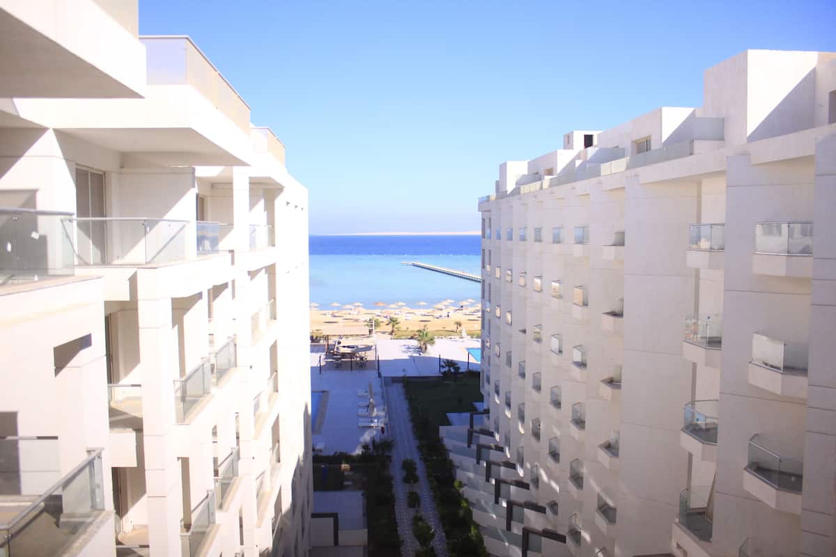 A high-rise building with balconies overlooking a beach and a pier.