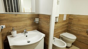 A bathroom with a white sink, a mirror, a toilet, and a bidet. - Entire apartment in the center of Palermo (Palermo)