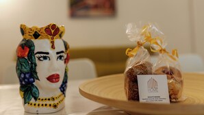 A ceramic figurine with a crown and floral design, a plate with biscotti, and a small card with text. - Entire apartment in the center of Palermo (Palermo)