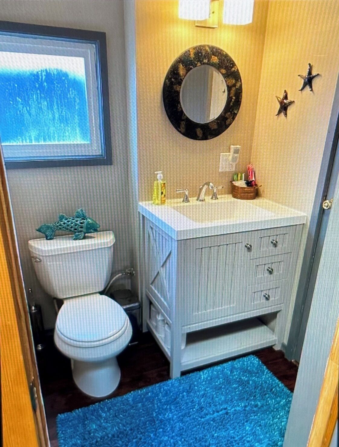 Une petite salle de bain comprenant des toilettes, un lavabo et une fenêtre située au-dessus des toilettes.