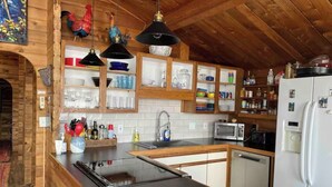A rustic kitchen with wooden cabinets, a black countertop, a sink, a microwave, and a refrigerator. - Picturesque Family-Friendly Beach Home! Sunrises @ Sandy Point (Ferndale)