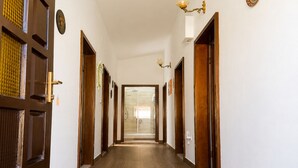 Un couloir avec des portes en bois, un sol carrelé et des luminaires fixés au mur.