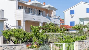 Un bâtiment moderne à deux étages, doté de balcons, d’un mur en pierre et d’une clôture en métal.