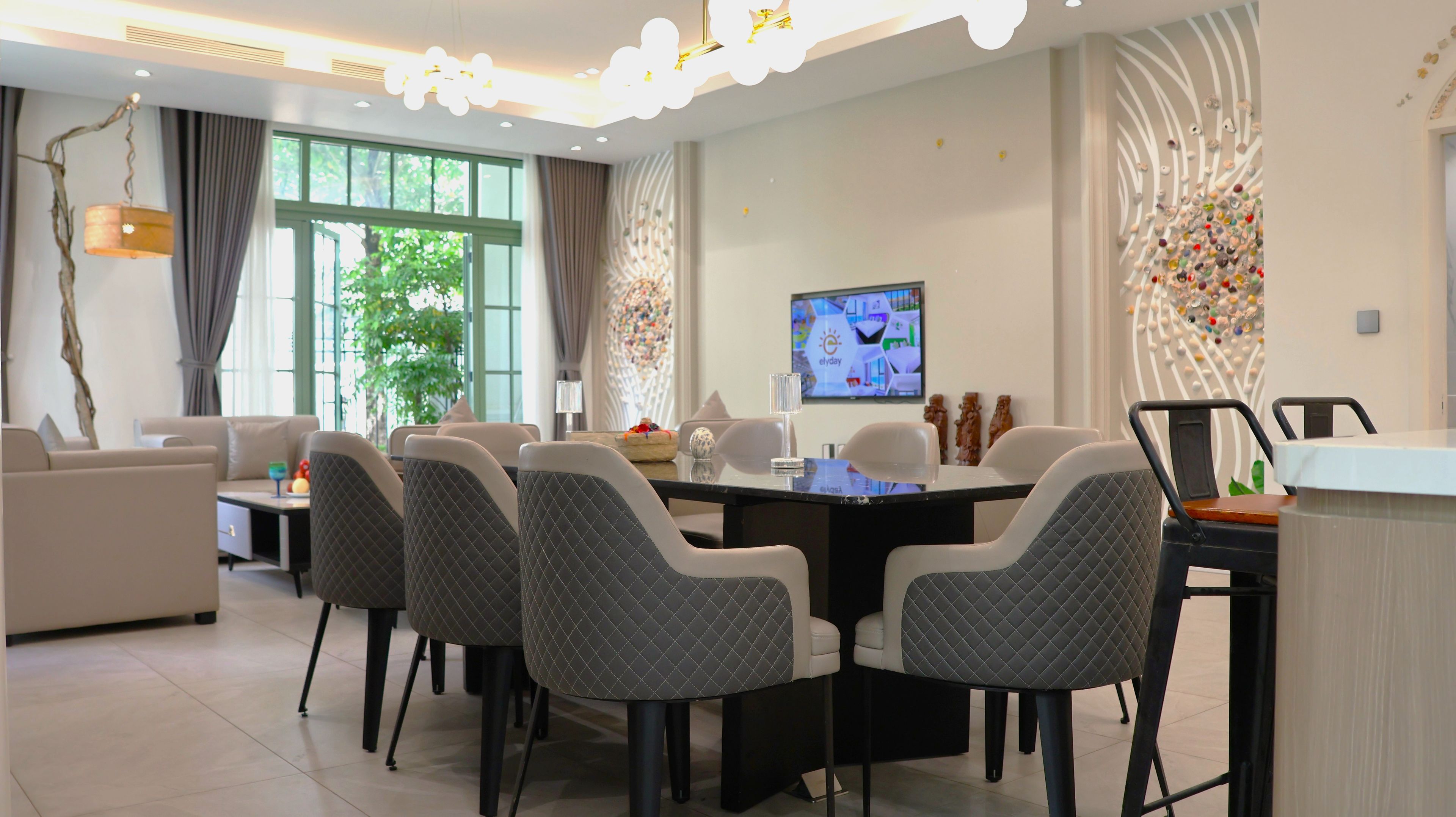 A modern dining area with a round table, six chairs, and a television screen.