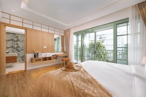 A modern bedroom with a large bed, a desk, a chair, and a view of the outdoors through a large window. - Elyday Villa - Bai Khem Beach, Phu Quoc (Phu Quoc)