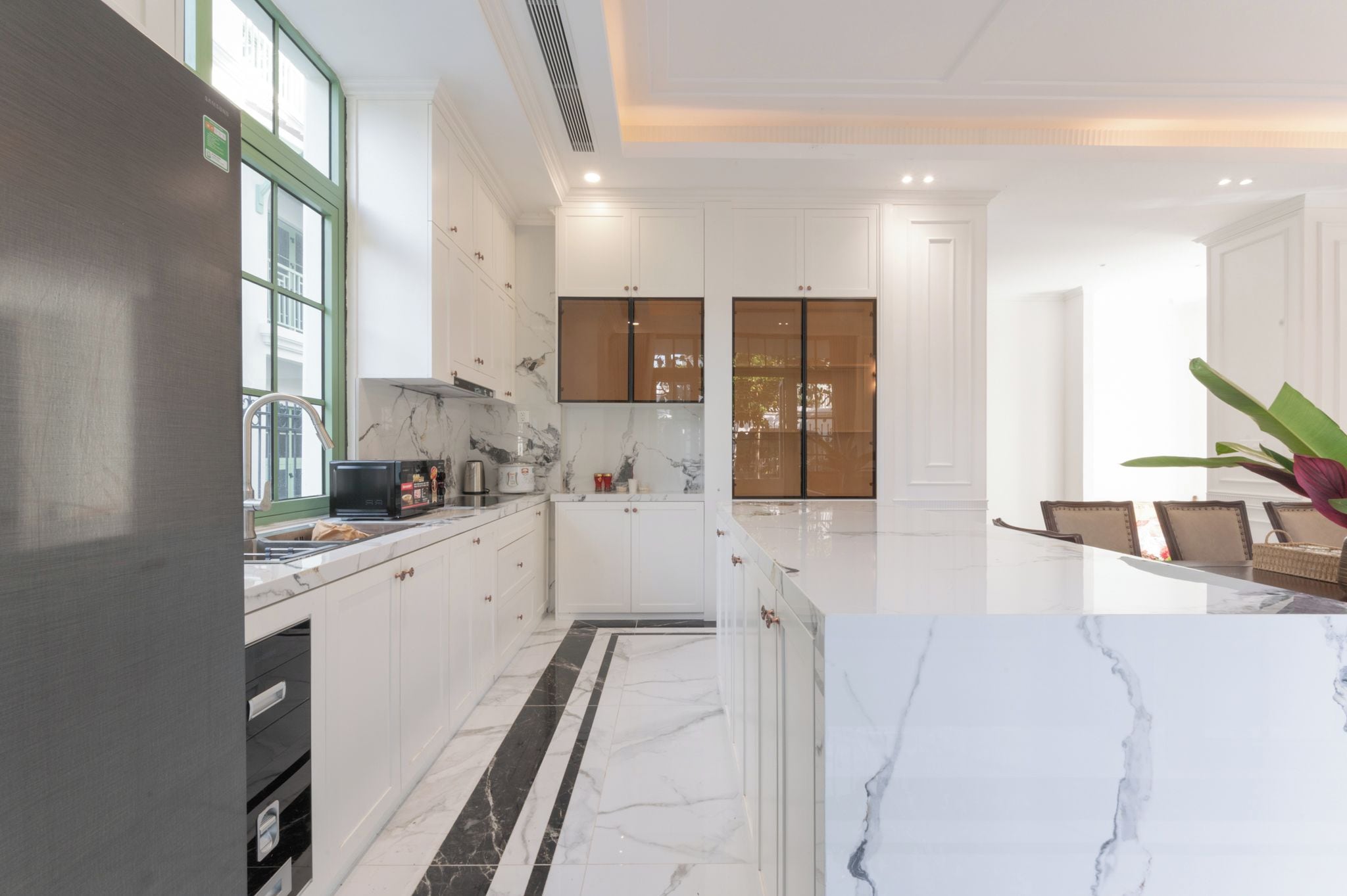 Una cocina moderna con armarios blancos, encimera de mármol y suelo a rayas negras y blancas.