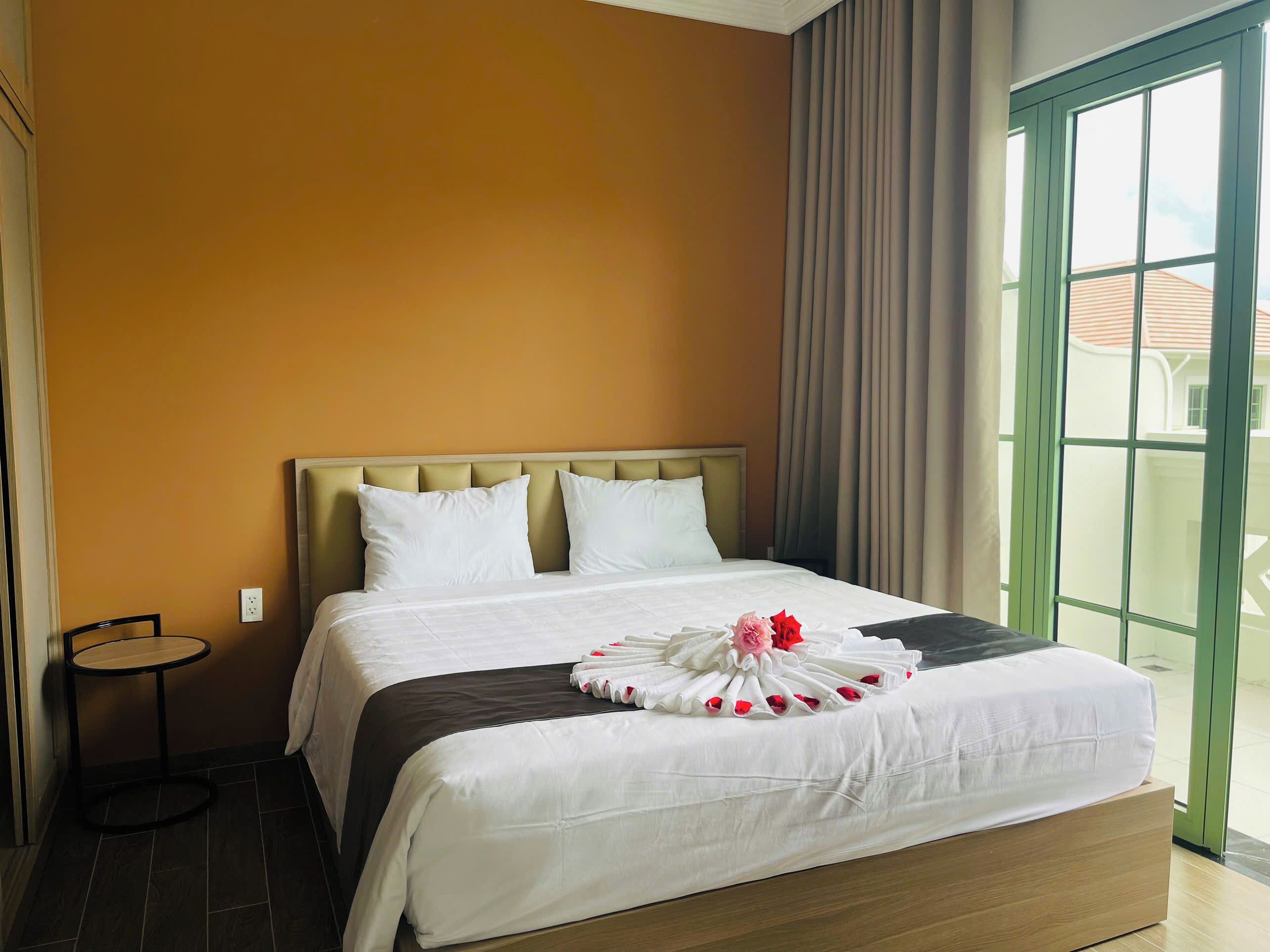 A hotel room with a bed, a round table, and a view of the outside.