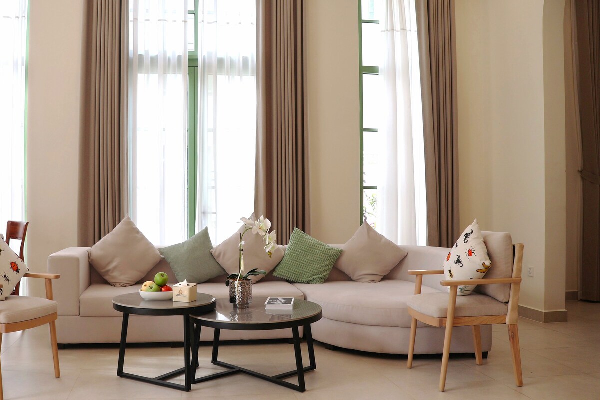 A living room with a sofa, two armchairs, a coffee table, and a vase with flowers.