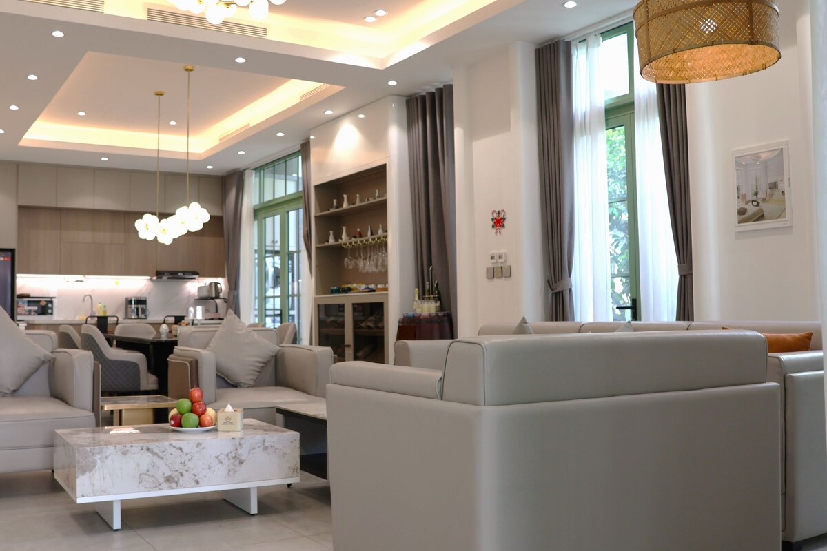 A modern living room with a sofa set, a coffee table, and a kitchen in the background.