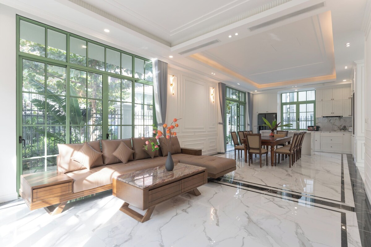 A spacious living room with a large sofa, a coffee table, and a dining area with chairs.