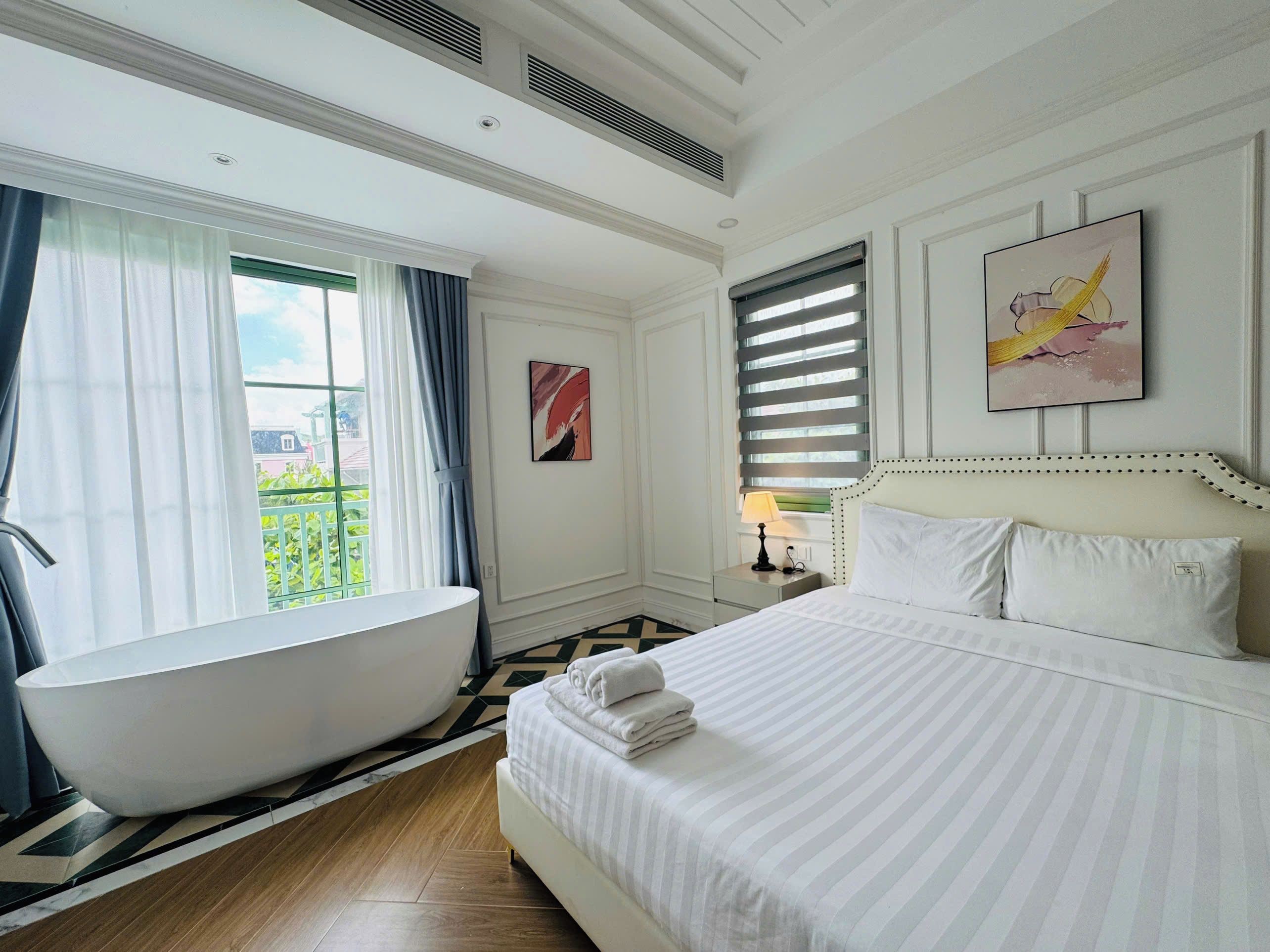 A hotel room with a large bed, a bathtub, and a view of the outdoors.