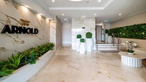 A modern lobby with a marble floor, a reception desk, and a staircase leading to upper floors. - StayAU Spacious 2BR Stunning Sunset Views (Box Hill)
