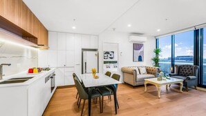 A modern apartment with a kitchen, dining area, and living room. - StayAU Spacious 2BR Stunning Sunset Views (Box Hill)