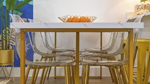 Un comedor con una mesa blanca, sillas transparentes y un espejo con marco dorado.