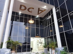 A modern building with a glass facade, a prominent 'DCV' sign, and a 'PARTNERS RE' sign visible through the entrance. - Doncont Homes and Apartments (Yenagoa)