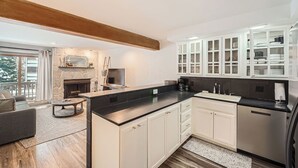 A modern kitchen with white cabinetry, a black countertop, and a built-in stove.