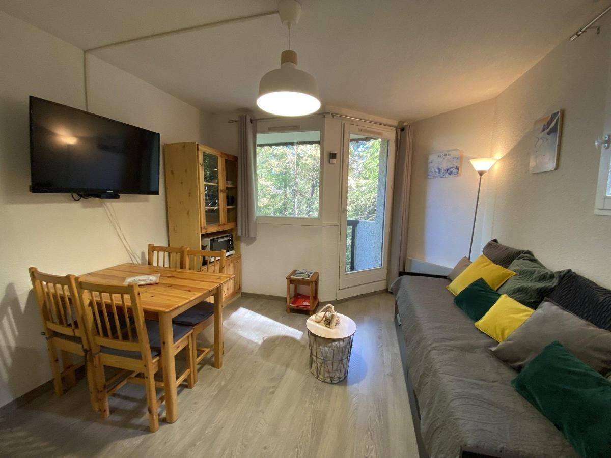 A compact living space with a dining table, chairs, a sofa, a TV, and a small side table.