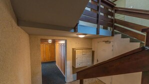 A staircase leading to a second floor, a set of wooden lockers, and a door with a sign.
