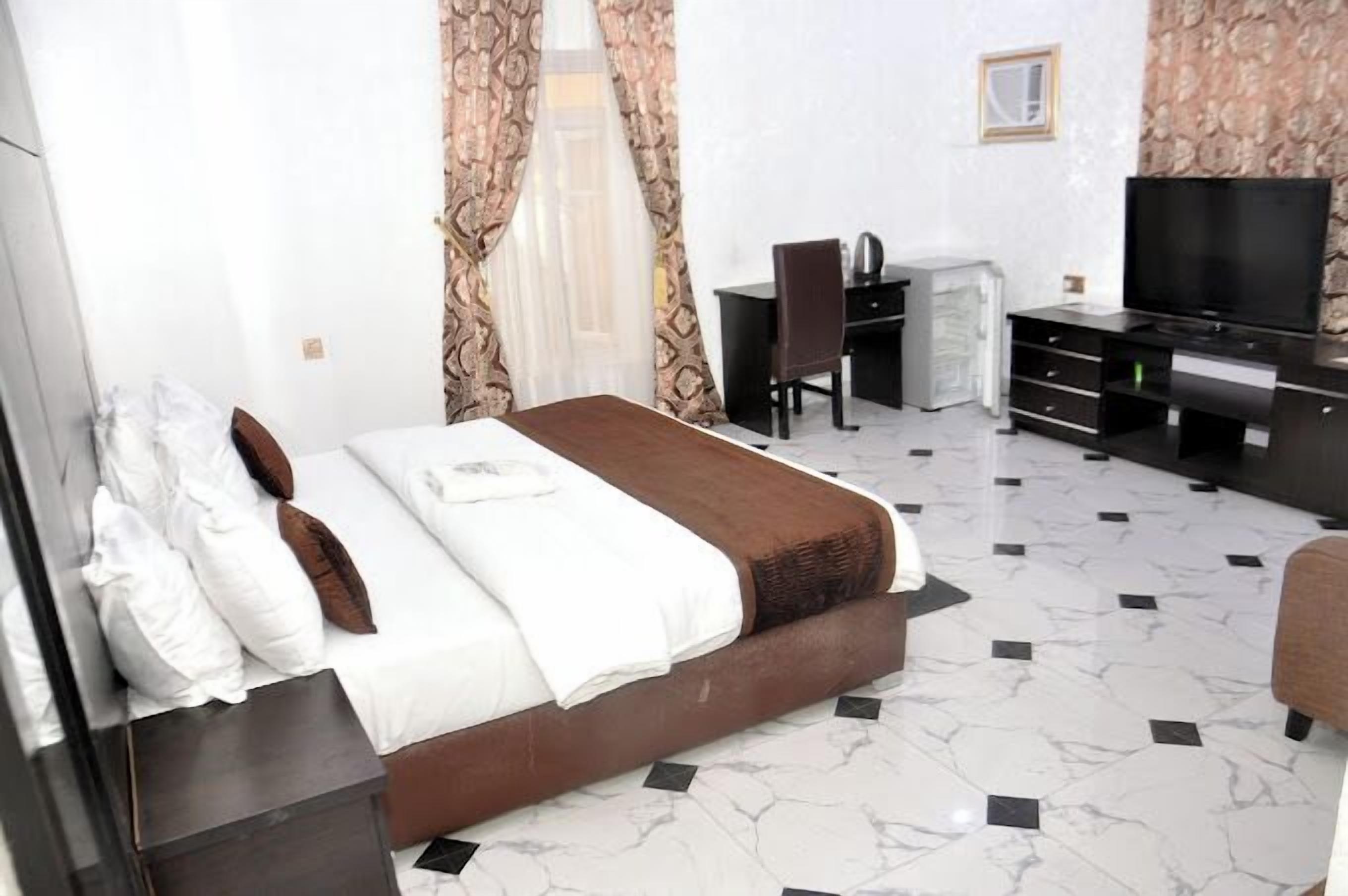Una camera d'albergo con un letto, una scrivania, una sedia e una televisione.