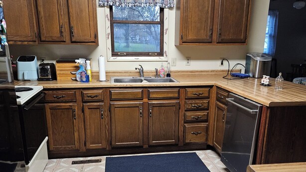 A kitchen with wooden cabinets, a window with a view, a clock, and a tiled floor. - Family-Friendly Home in Davis (Davis)