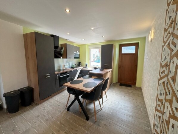 A compact kitchen with modern appliances, a dining table with chairs, and a window providing natural light.