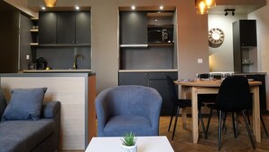 A modern kitchen with built-in appliances, a dining area with a table and chairs, and a cozy seating area with a sofa and armchair.