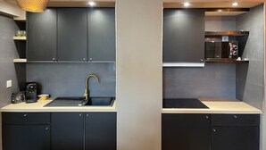 A modern kitchen with dark cabinets, a sink, and a coffee machine.