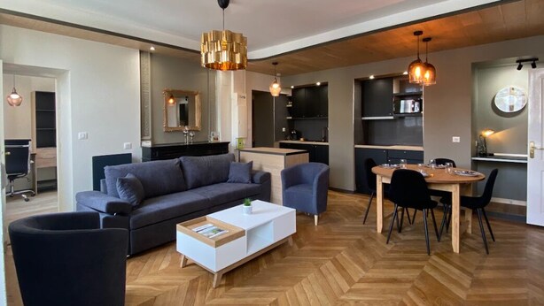 A modern living room with a sofa, coffee table, and dining area.