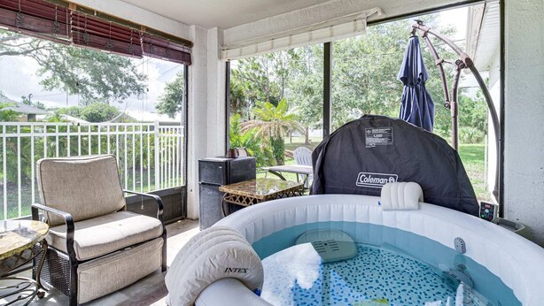 Ett takförsett utomhusområde med en bubbelpool, en stol, ett bord och ett Coleman-tält.