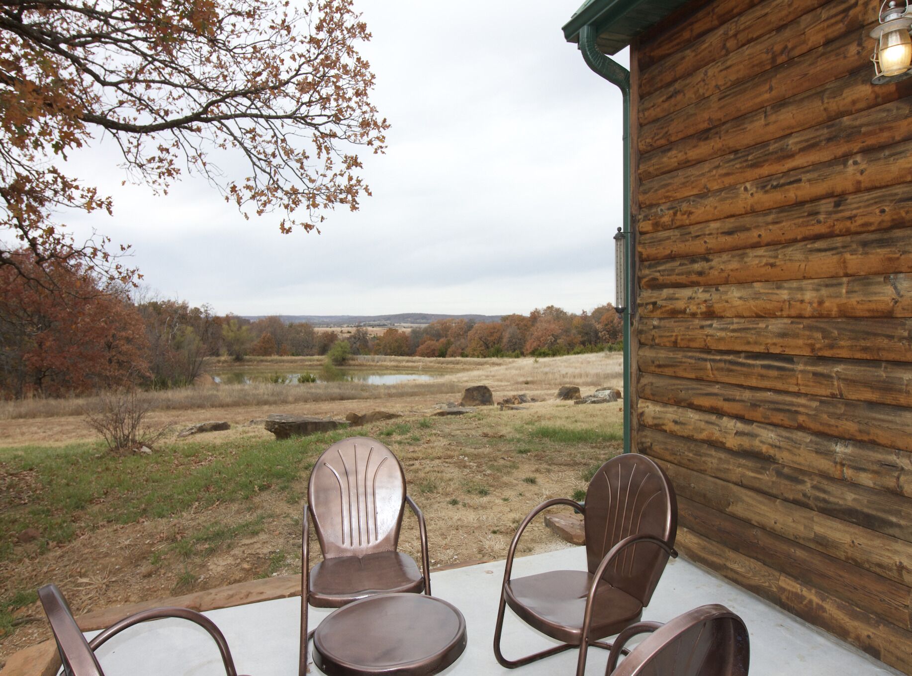 Une cabane en bois dotée d’un porche aménagé avec deux chaises et une table.